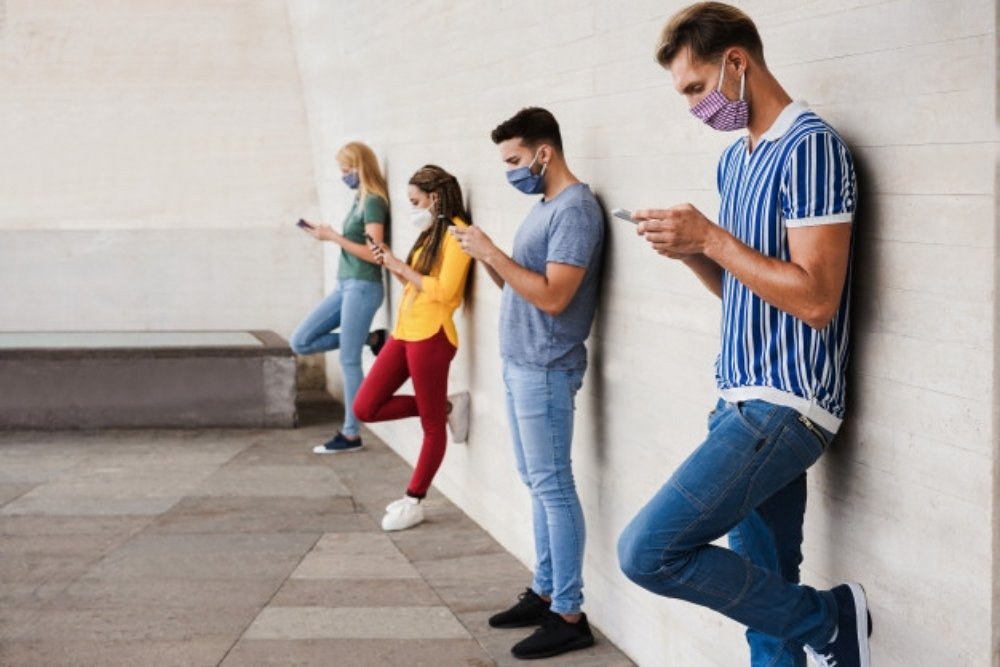 blog-1611486764young-people-wearing-face-safety-masks-using-smart-mobile-phones-while-keeping-social-distance-coronavirus-outbreak_166273-566 (1).jpg